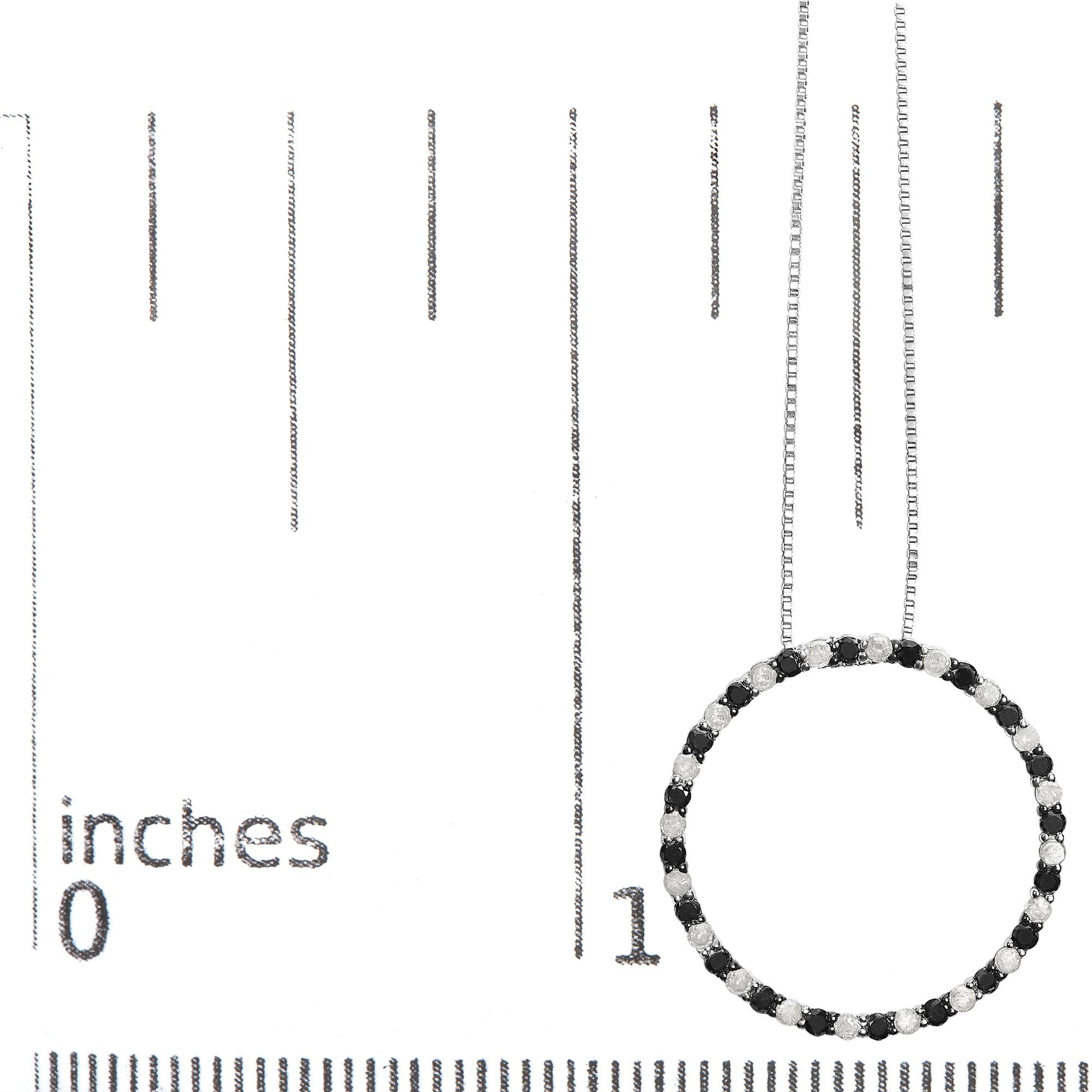Close-up front view of a white metal circular necklace pendant with alternating black and white round prong-set gemstones, shown on a scale.