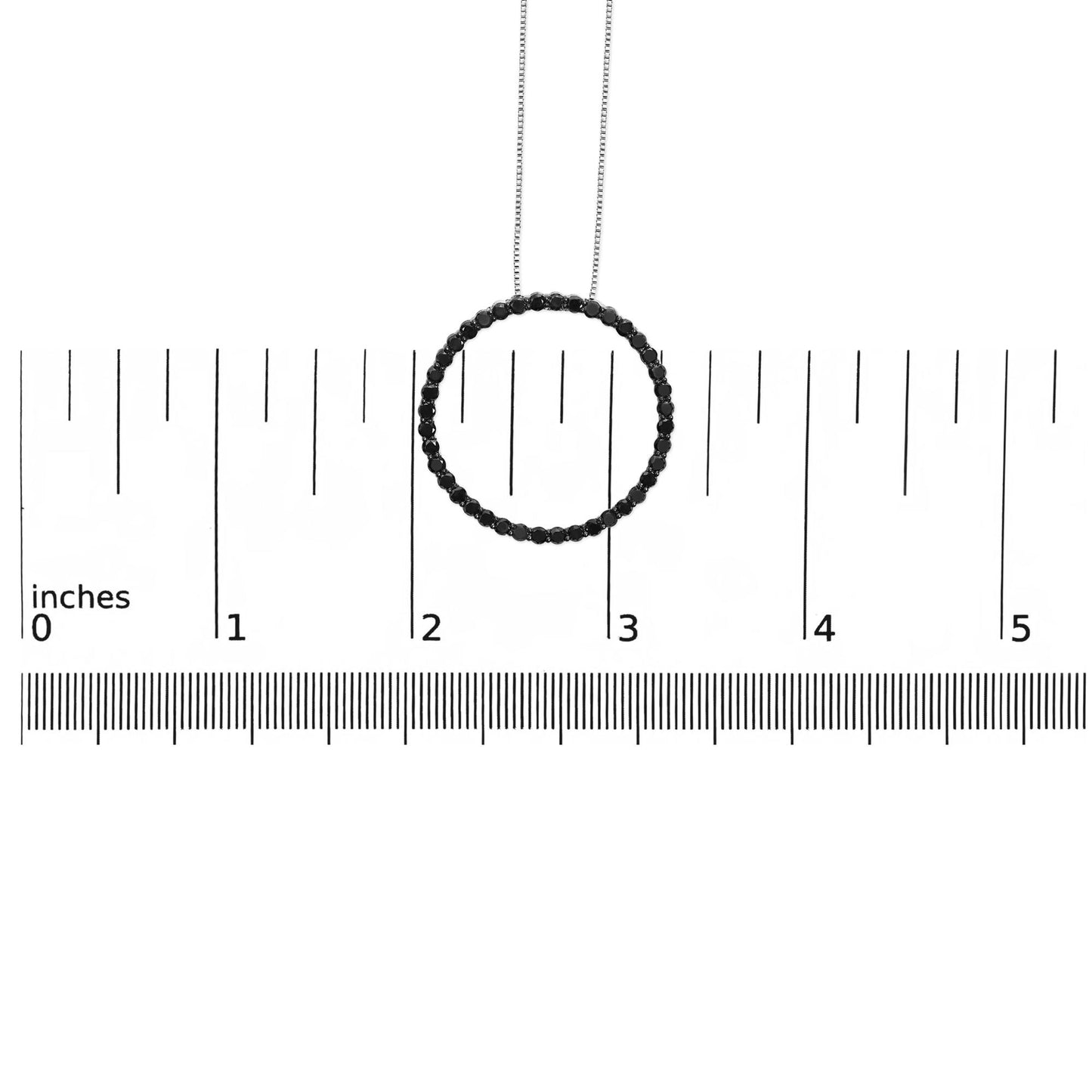 Pendant necklace with a circular design of round black gemstones in shared prong setting, displayed on a ruler for size reference, shot from the front.