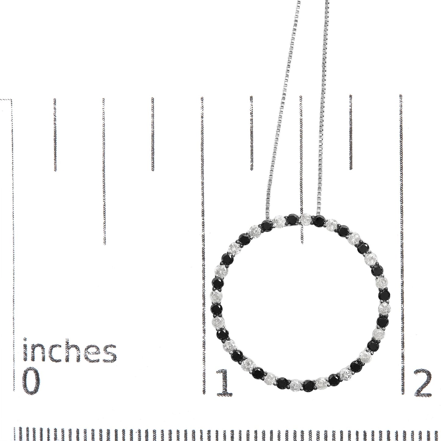 Top-down close-up of a white necklace with alternating black and white round prong-set gemstones forming a circle, shown on a ruler for size reference.