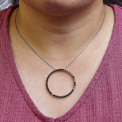 Front-facing close-up of a white metal necklace with a large circular pendant featuring black round gemstones, worn on a model.