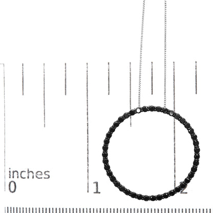 Round-shaped necklace with black gemstones in shared prong setting on white metal, shown hanging in front of a ruler for size reference, photographed from front angle.