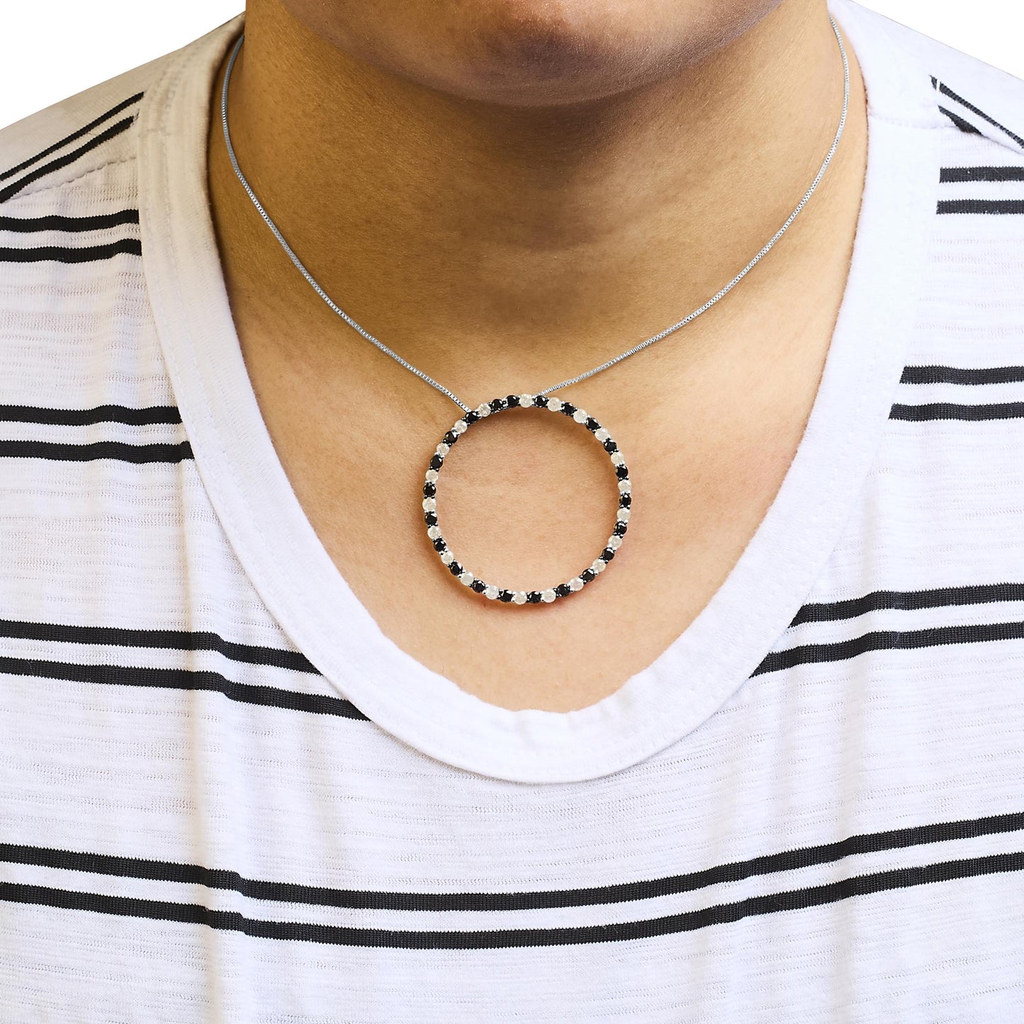 White metal necklace with a circular pendant featuring alternating black and white round gemstones in prong settings, worn on a model, front-facing angle.