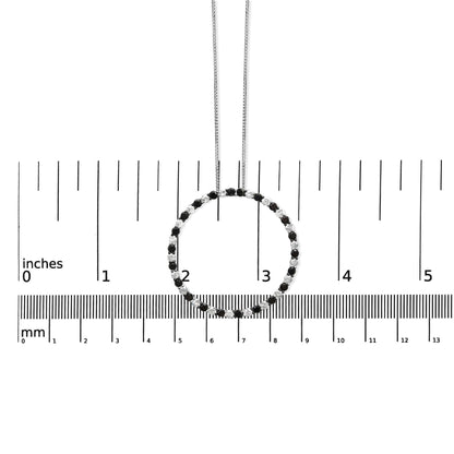 Front view of a white metal circle necklace with alternating black and white round gemstones in prong settings, displayed on a ruler for size reference.