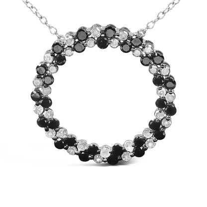 Close-up front view of a white metal necklace pendant featuring a circular design with alternating round black and white gemstones in prong settings.