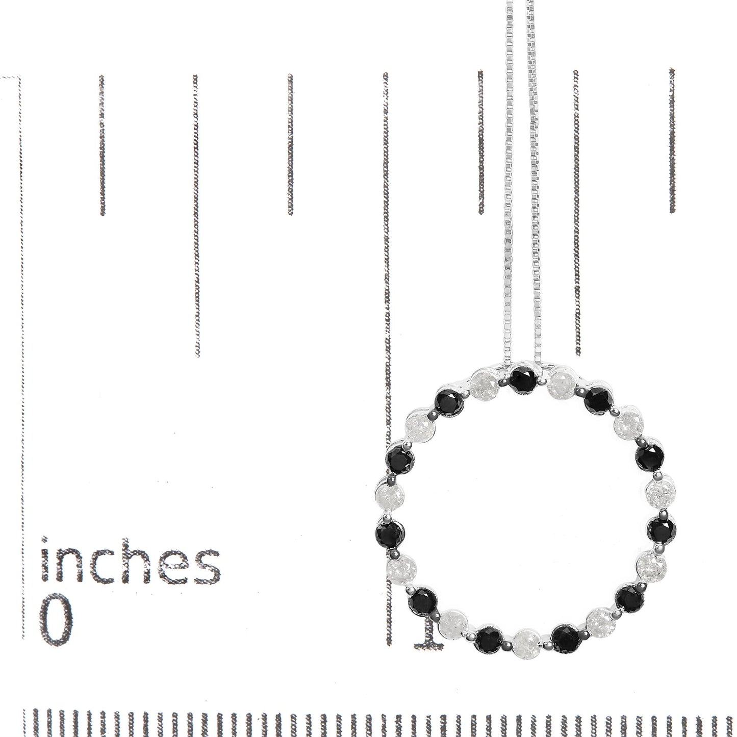 White metal necklace displayed on a ruler for size reference, featuring a circular pendant with alternating round black and white gemstones in prong settings, shown from the front angle.