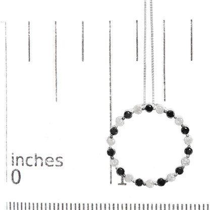 White metal necklace displayed on a ruler for size reference, featuring a circular pendant with alternating round black and white gemstones in prong settings, shown from the front angle.
