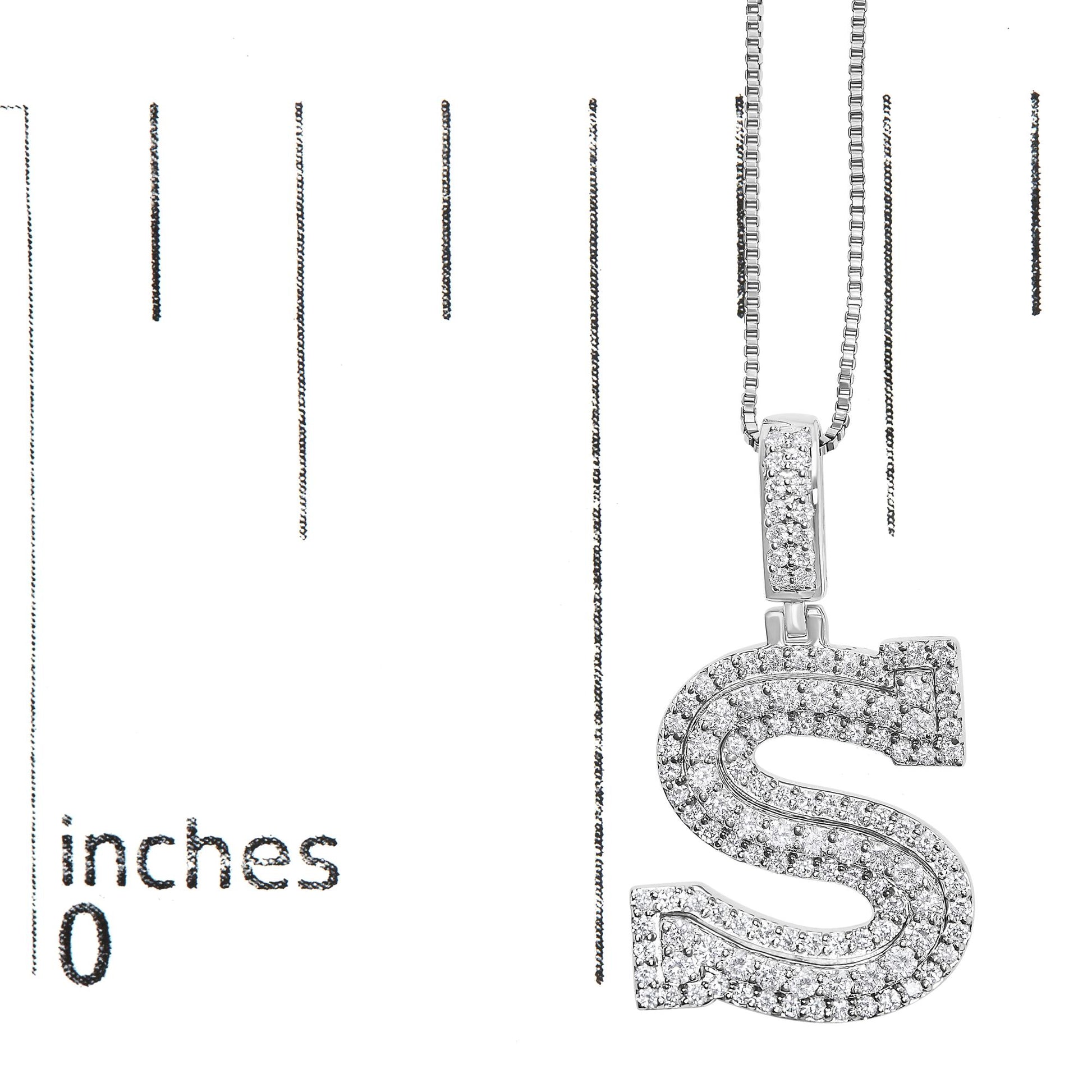 Close-up front angle of a white metal necklace with an 'S'-shaped pendant encrusted with round white gemstones, shown on a scale.