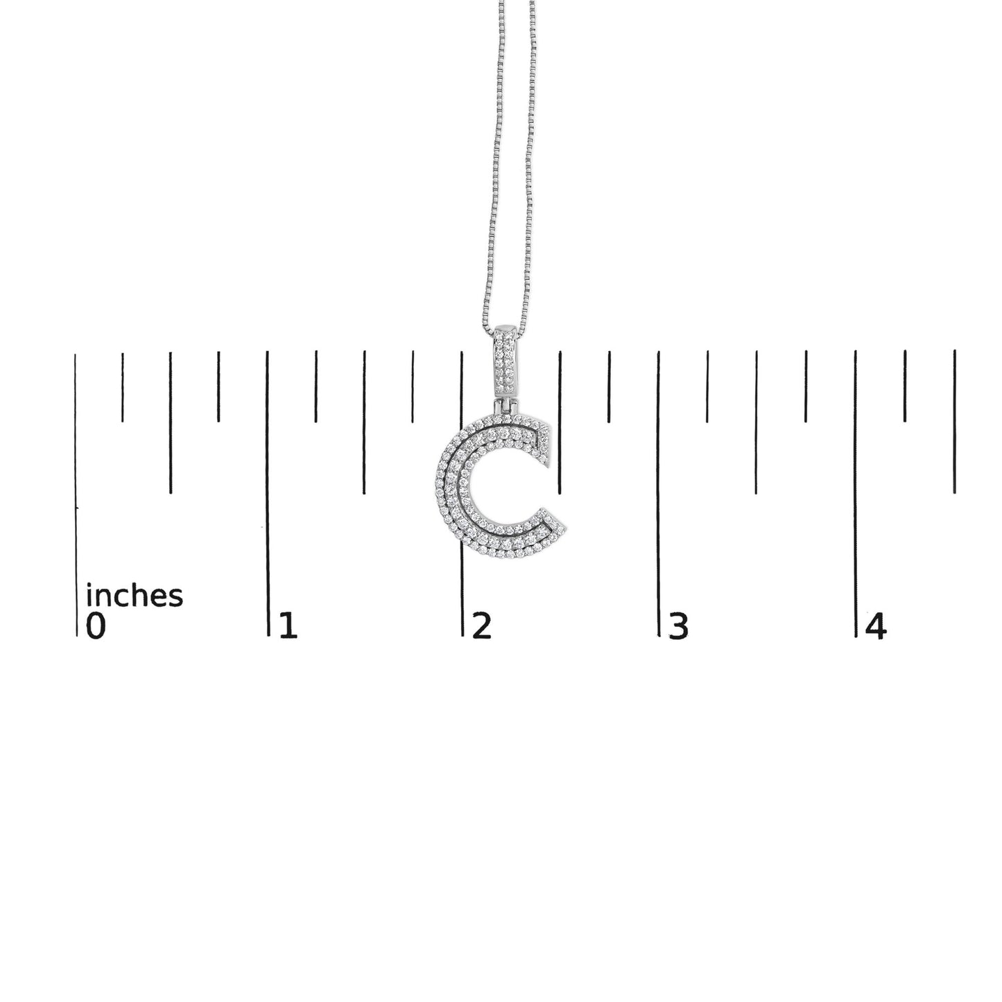 Front view of white metal necklace with C-shaped pendant covered in two rows of round white gemstones, photographed on a ruler for size reference.