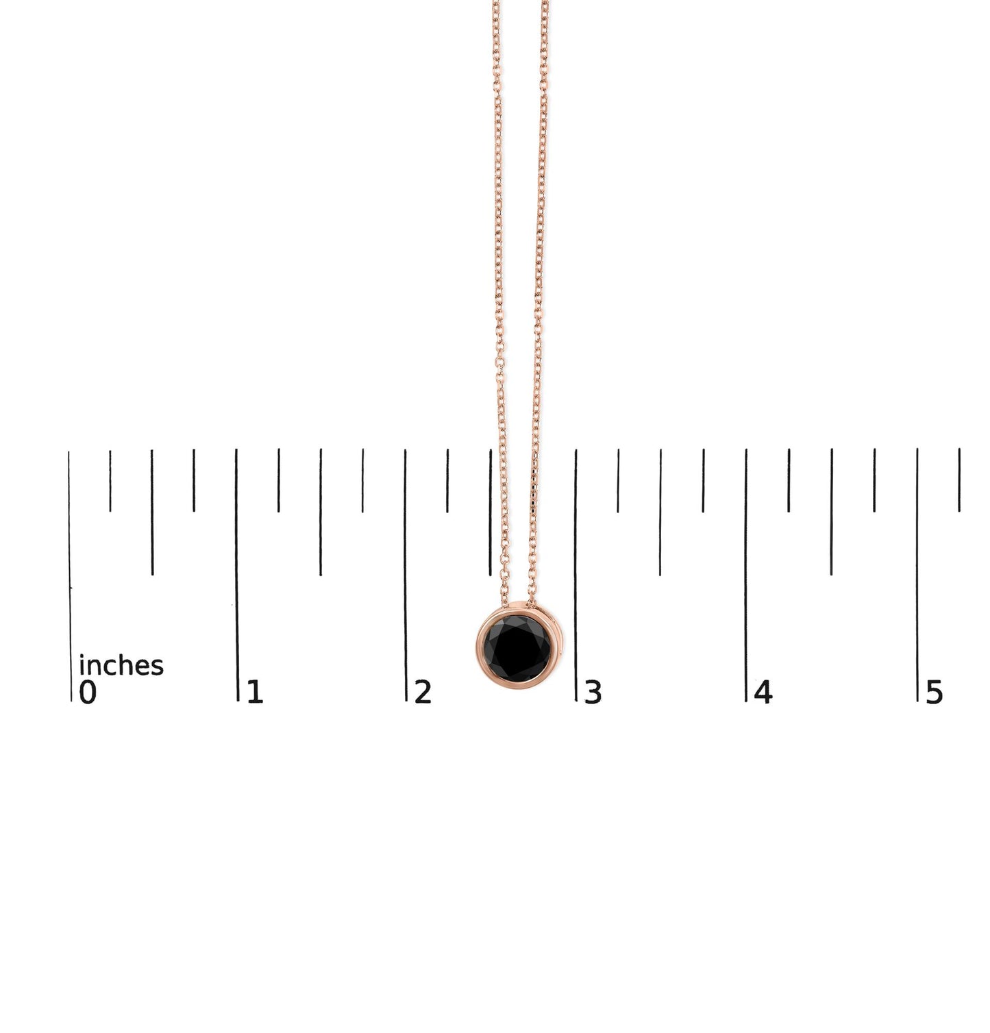 Rose metal necklace with round black gemstone in bezel setting, hanging vertically above a ruler for size reference, front view.
