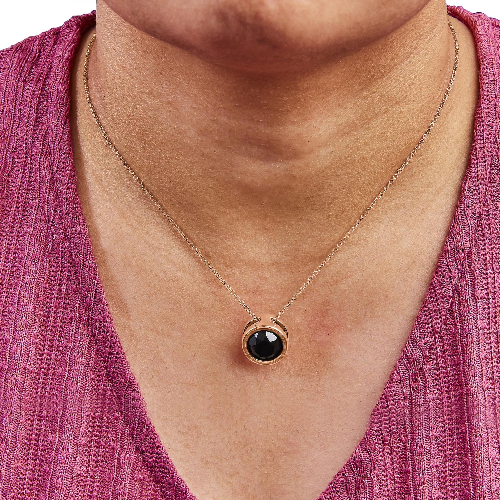 Rose metal necklace with round black gemstone in bezel setting, shown on a model from front angle.