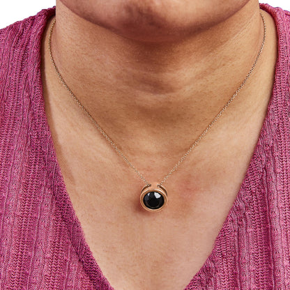 Rose metal necklace with round black gemstone in bezel setting, shown on a model from front angle.