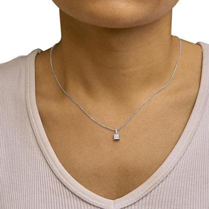 Close-up front view of a white metal necklace with a pendant featuring four princess-shaped white gemstones in an invisible setting, shown worn on a model.