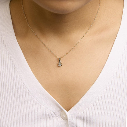 Close-up front view of a yellow metal necklace with a round white gemstone in a prong setting, shown worn on a model.