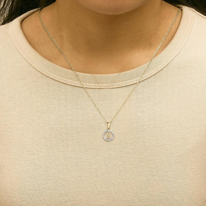 Close-up front view of a model wearing a yellow metal necklace with a round pendant surrounded by white gemstones in a shared prong setting.