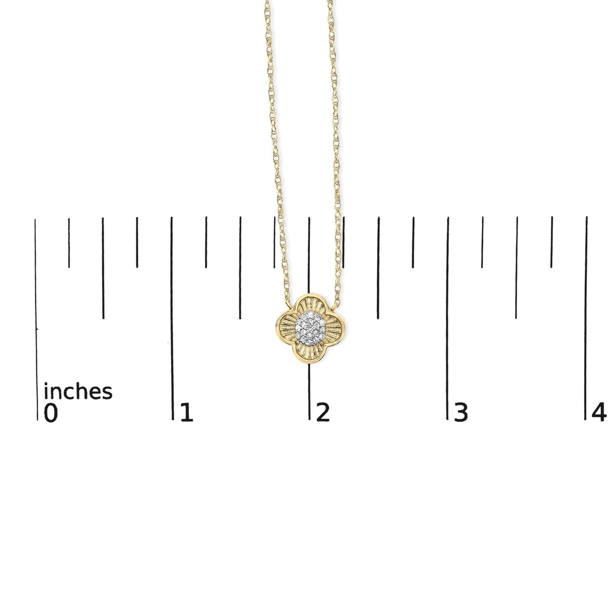 Yellow metal necklace with a clover-shaped pendant featuring round white gemstones in prong settings, shown on a ruler scale, front view.