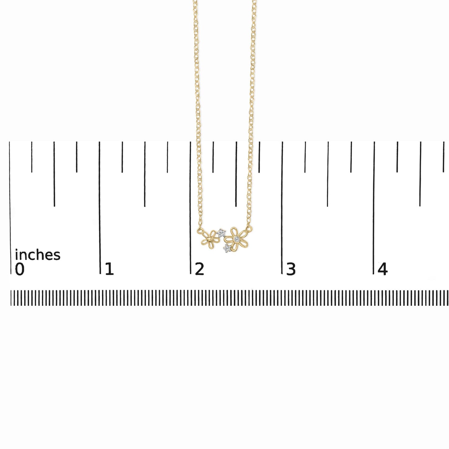 Yellow metal necklace with two open flower-shaped pendants each accented with small white gemstones, shown on a scale with a front-facing angle.