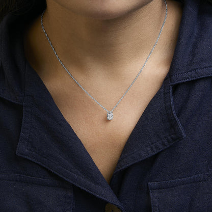 Necklace with a white metal chain and a pendant featuring multiple round white gemstones in prong settings, shown worn on a model from a front angle.
