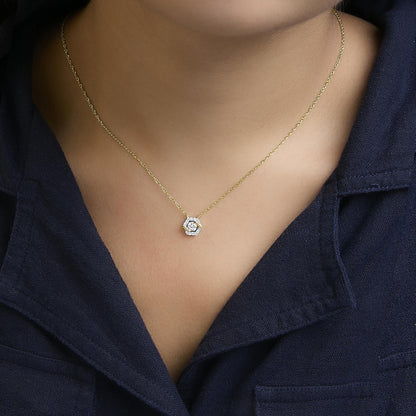 Close-up front view of a necklace with a yellow metal chain and a hexagonal pendant featuring white round gemstones in prong settings, worn by a model.