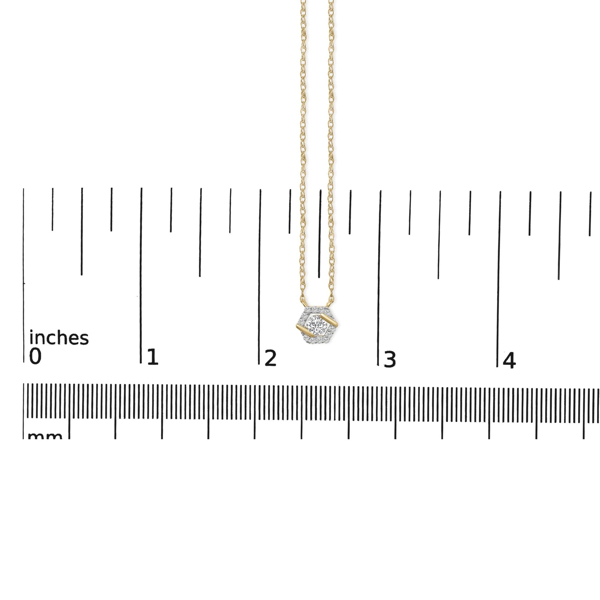 Yellow metal necklace with a hexagonal-shaped pendant featuring one large round white gemstone and surrounding smaller round white gemstones, shown on a ruler scale from a top-down angle.