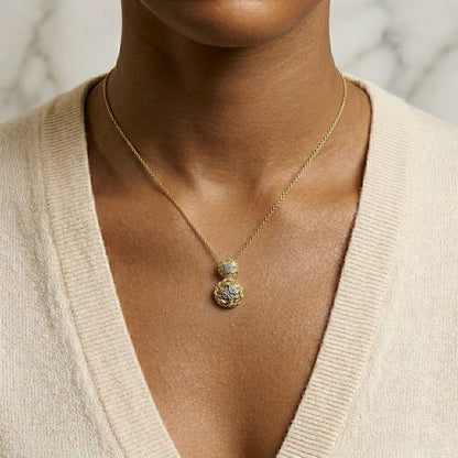 Yellow metal necklace with two round pendants, each featuring a white gemstone in a 4-prong setting, shown worn on a model from a front angle.