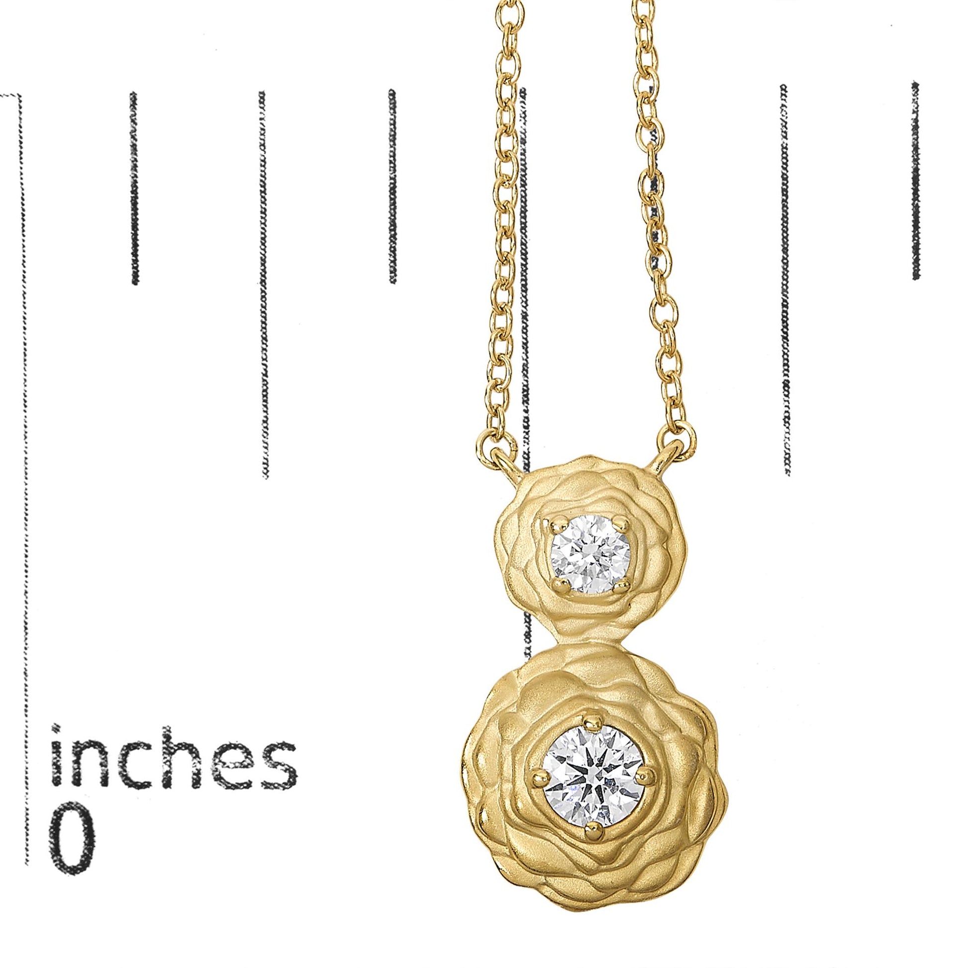 Close-up front view of a yellow necklace pendant with two round white gemstones in 4-prong settings, shown on a scale.