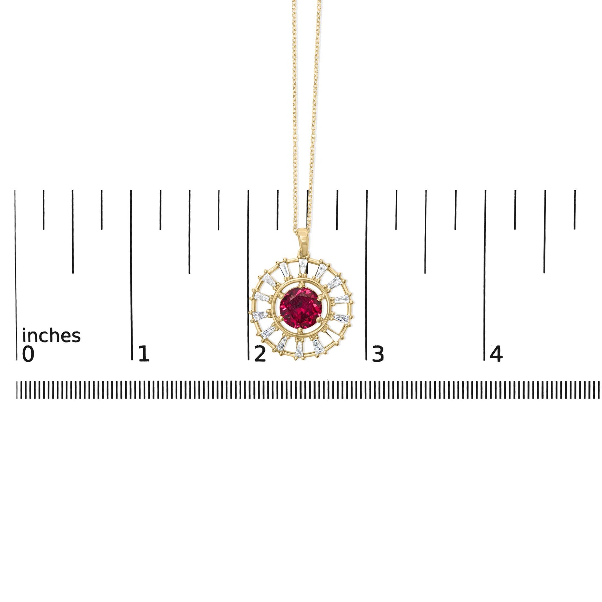 Close-up front view of a yellow metal necklace pendant with a round red gemstone center surrounded by baguette-shaped white gemstones, shown on a scale.