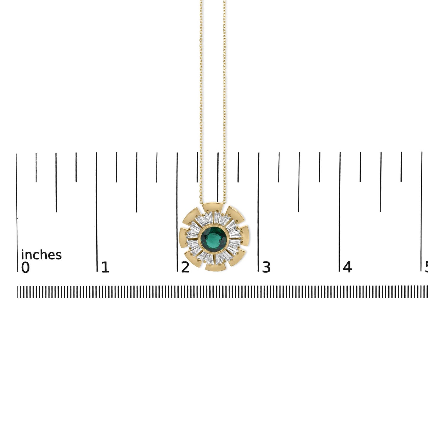 Close-up front view of a yellow metal necklace pendant shown on a scale. The pendant is circular with a large round green gemstone in the center, surrounded by a ring of white baguette-shaped gemstones in prong settings, and yellow metal fan-shaped accents around the edge. The pendant hangs from a fine chain.