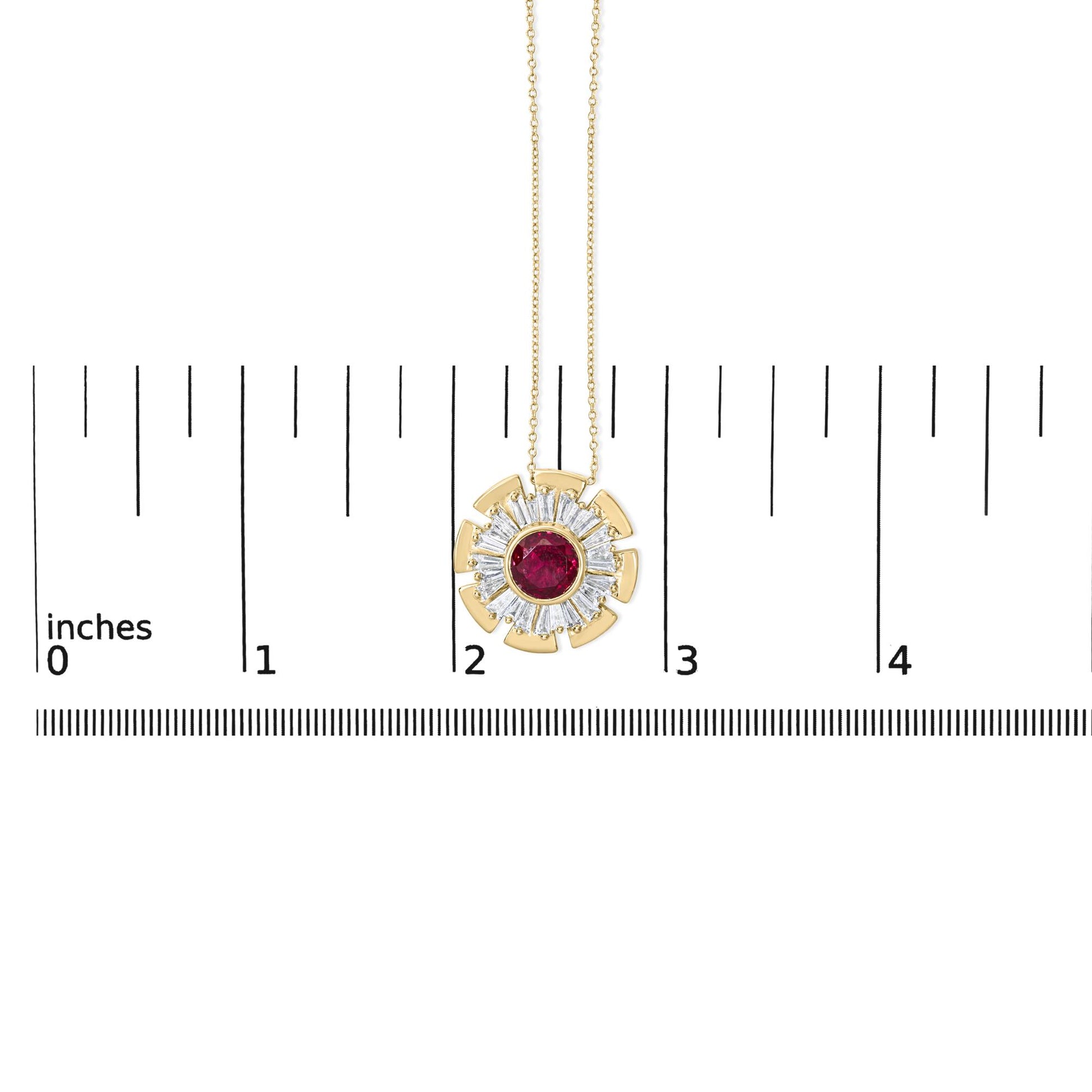 Close-up front view of a yellow metal necklace pendant with a round red gemstone bezel set in the center, surrounded by prong-set white baguette-shaped gemstones in a circular pattern, shown on a scale.