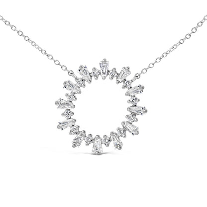 Close-up front angle of a white metal necklace pendant in a circular shape, set with alternating baguette and round white gemstones, shown on a white background.