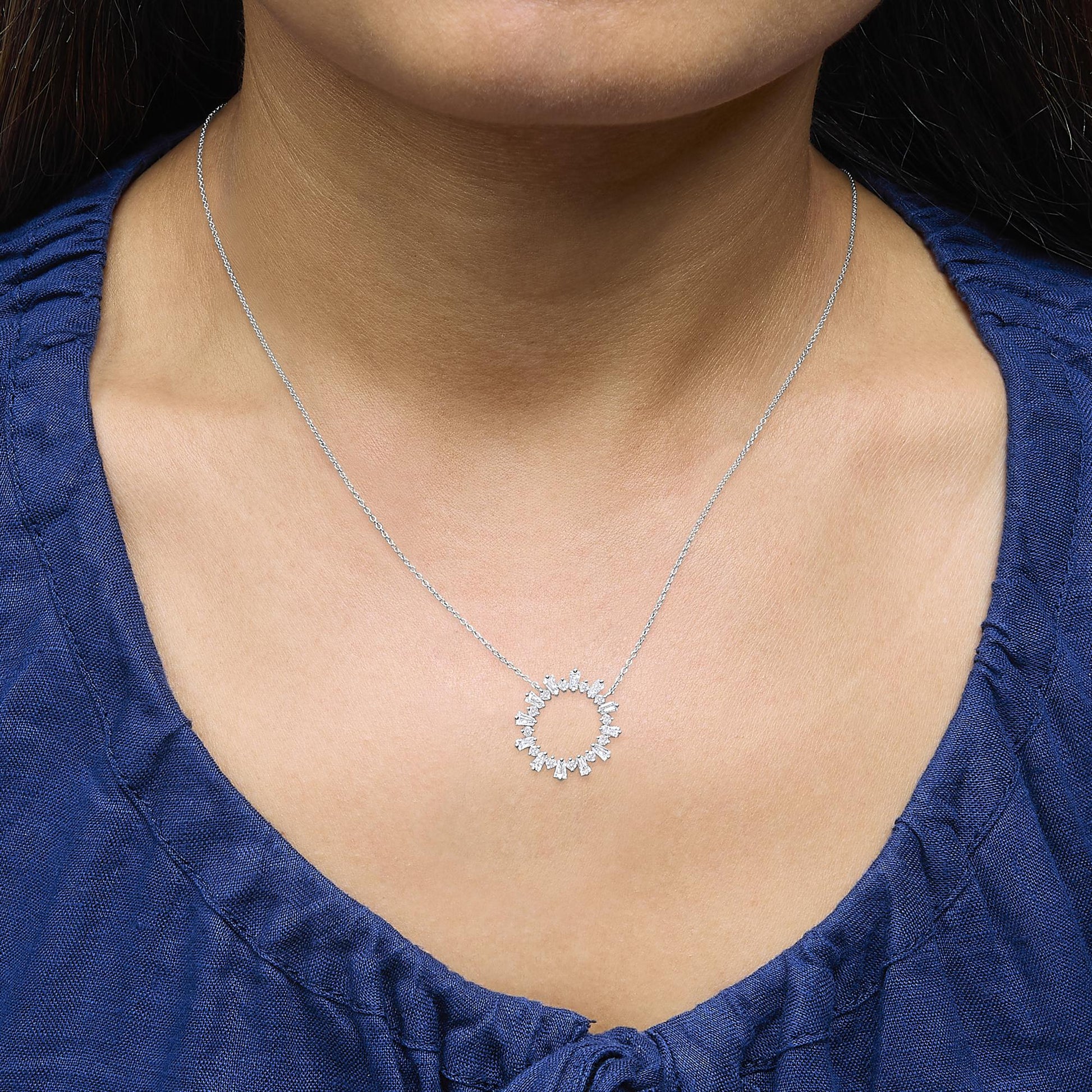 Close-up front view of a model wearing a white metal necklace featuring a circular pendant adorned with alternating round and baguette-shaped white gemstones in prong settings.