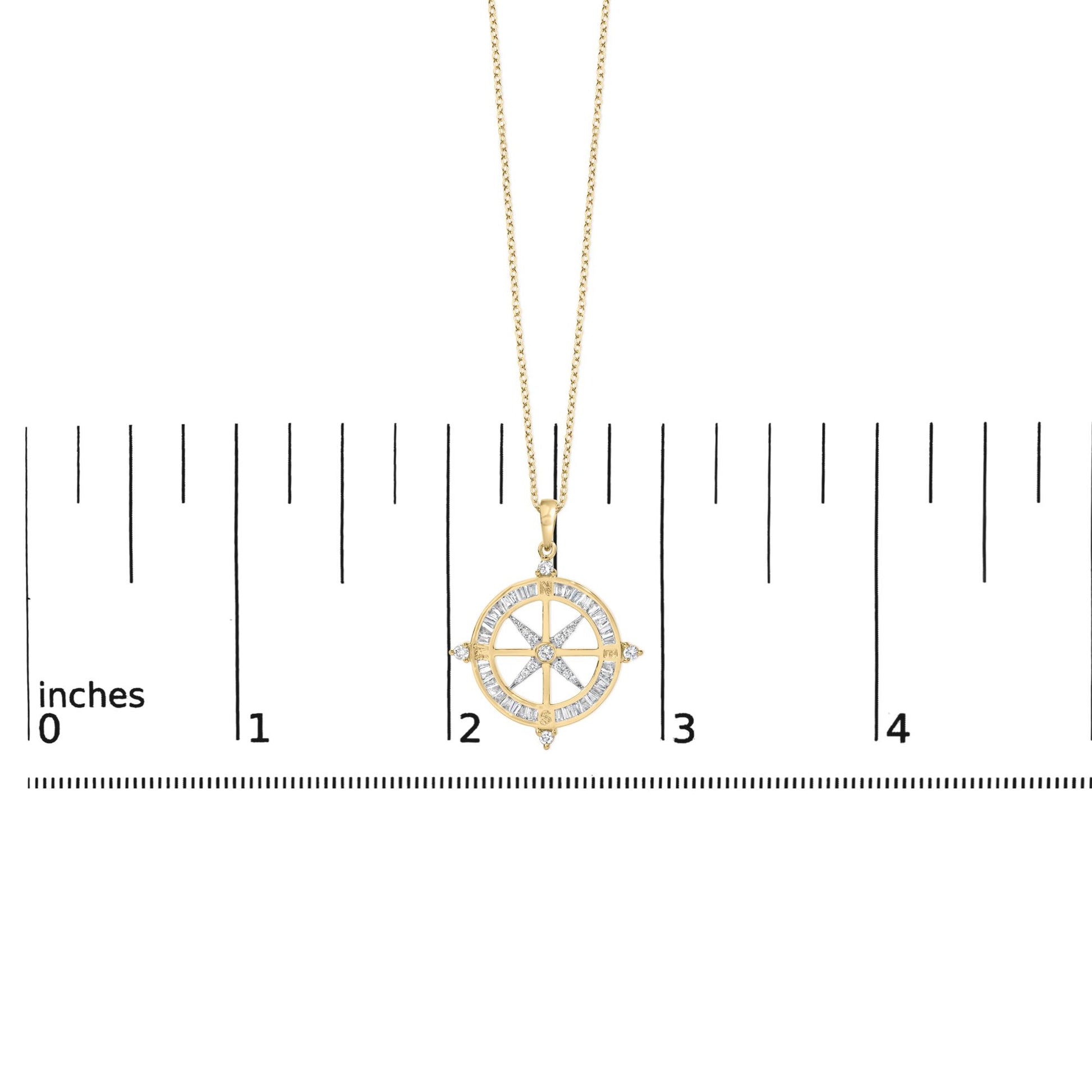Yellow metal necklace with a round compass-shaped pendant featuring white baguette and round gemstones, shown on a scale with a front angle.