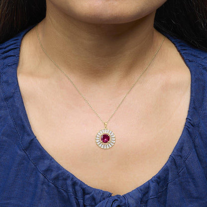 Yellow metal necklace with a round pendant featuring a central red gemstone surrounded by white baguette-shaped gemstones in a channel setting, shown worn on a model from the front angle.