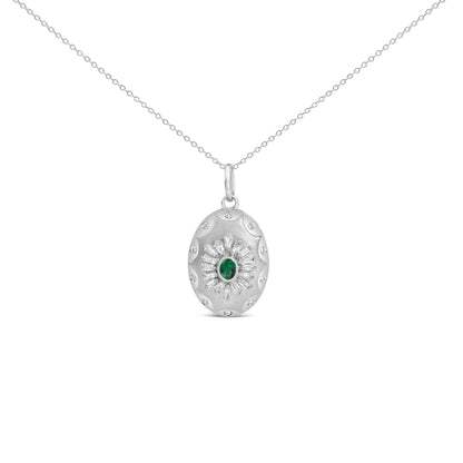 Close-up front view of a white metal necklace with an oval pendant featuring a central green gemstone surrounded by baguette and round white gemstones in prong and bezel settings.