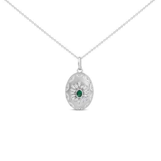 Close-up front view of a white metal necklace with an oval pendant featuring a central green gemstone surrounded by baguette and round white gemstones in prong and bezel settings.