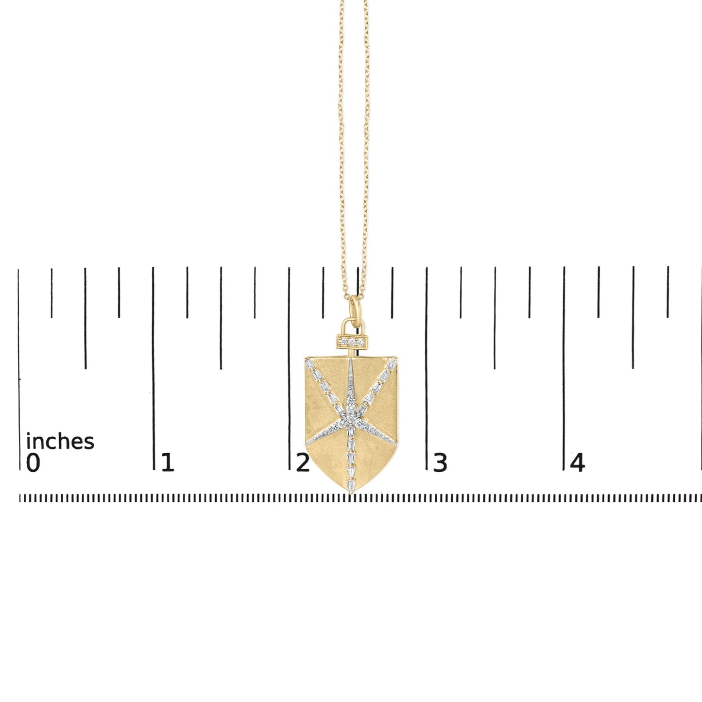 Close-up image of a yellow necklace pendant with a rectangular shape featuring white round and baguette gemstones arranged in a starburst pattern, shown on a scale.