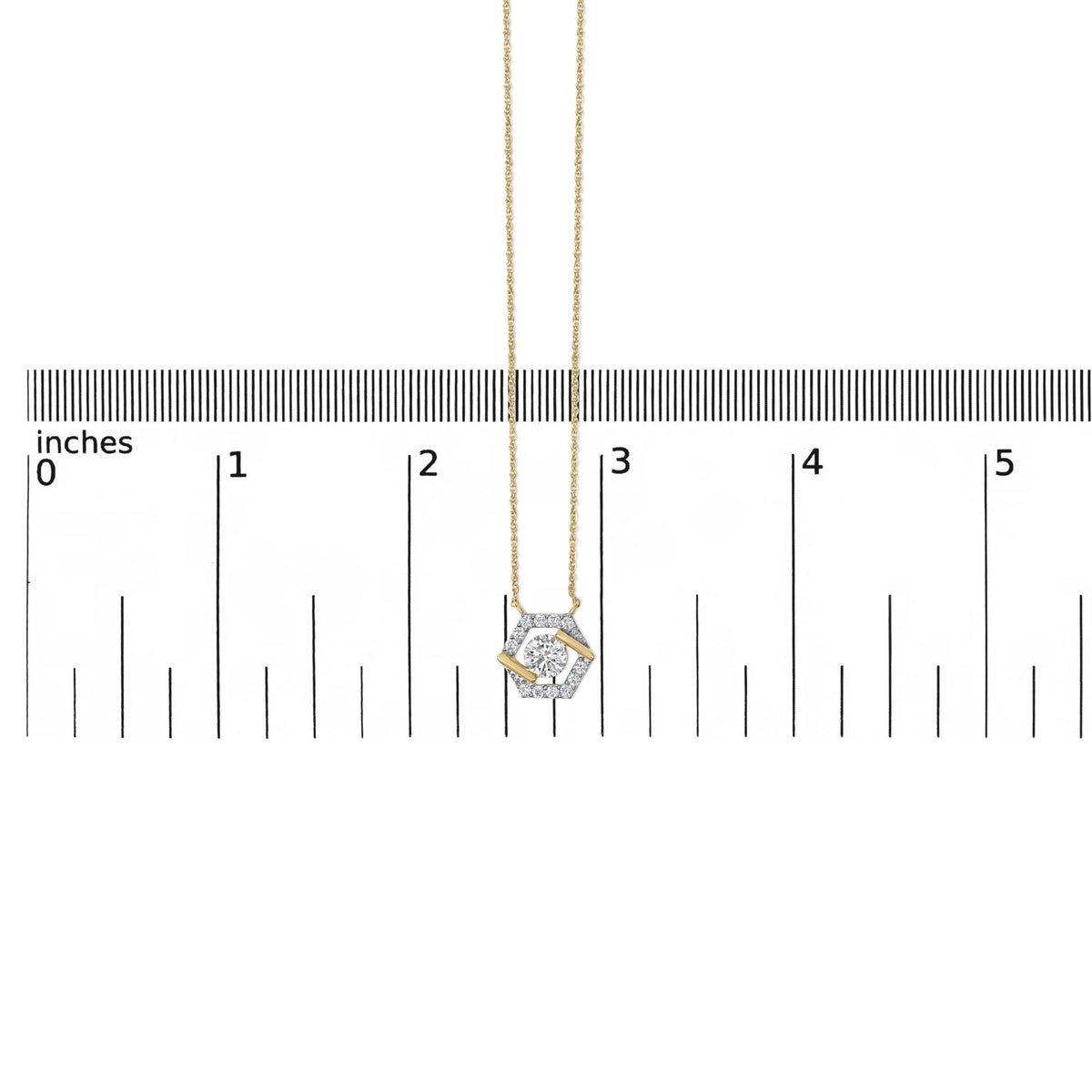 Close-up on a yellow necklace pendant with a hexagonal shape featuring multiple small white gemstones and one central larger white gemstone, shown hanging vertically on a scale.