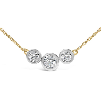 Close-up front angle of a yellow metal necklace with three round white gemstones in bezel settings, with the center gemstone larger than the two on the sides.