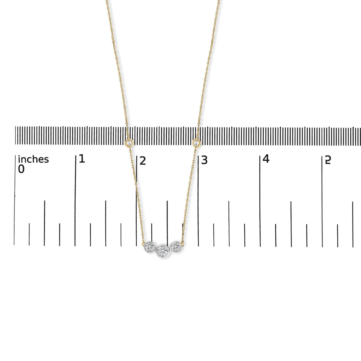 Close-up front view of a yellow necklace with round white gemstones in bezel settings, displayed on a ruler for scale.