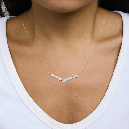 Close-up angled view of a model wearing a yellow metal necklace with a central pendant featuring multiple round white gemstones in bezel and prong settings.