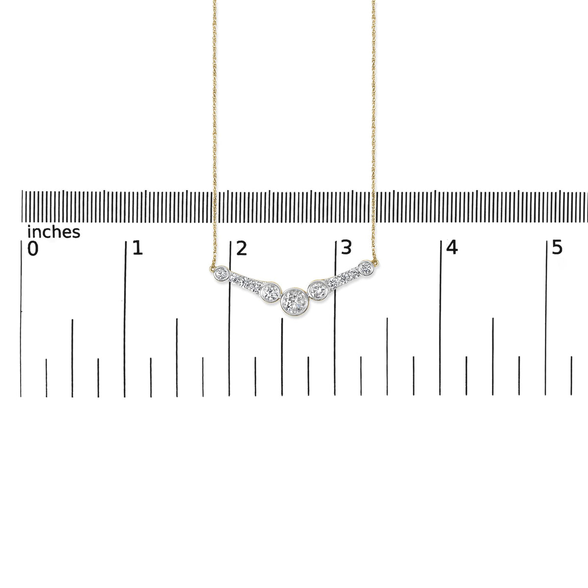 Close-up front view of a yellow metal necklace with a curved pendant featuring round white gemstones in bezel and prong settings, shown on a ruler scale.