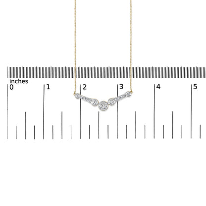 Close-up front view of a yellow metal necklace with a curved pendant featuring round white gemstones in bezel and prong settings, shown on a ruler scale.