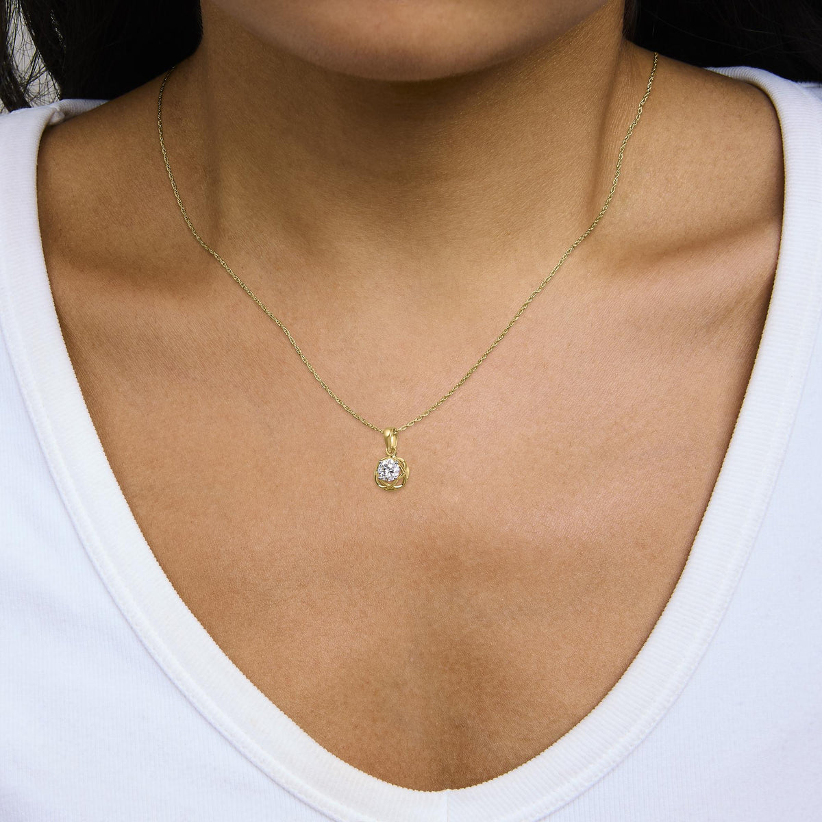 Close-up front view of a model wearing a yellow metal necklace with a round white gemstone pendant in a prong setting.