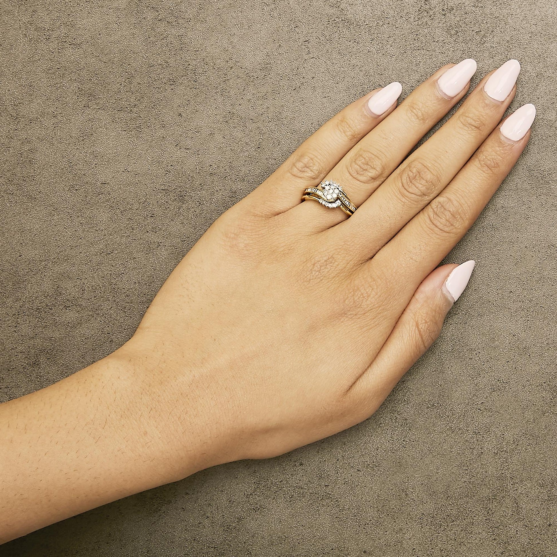 Close-up angled top view of a model's hand wearing a yellow and white metal ring with channel-set white baguette-shaped gemstones and prong-set round white gemstones.