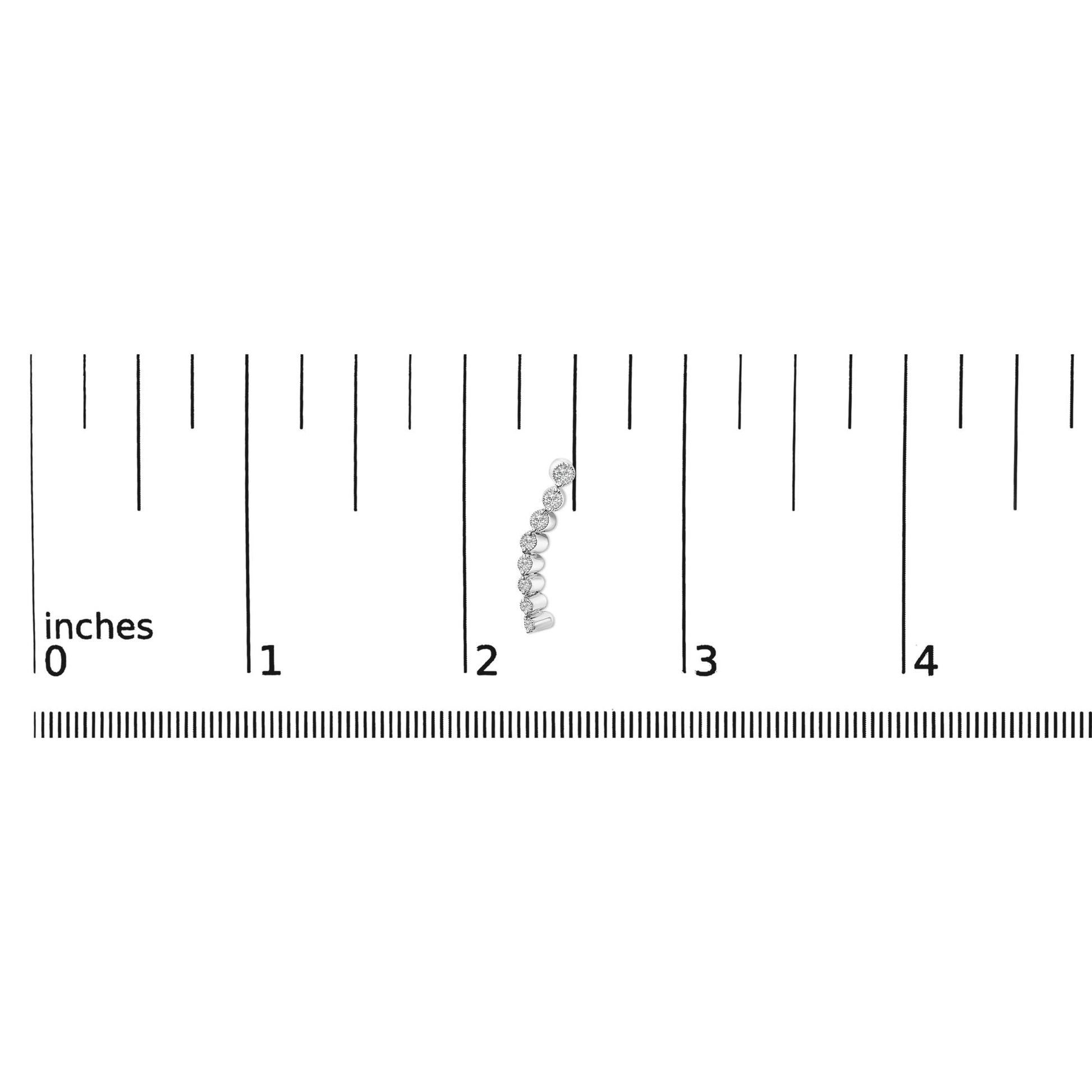 White metal earrings with a curved row of round white gemstones in prong settings, shown on a ruler scale from a front angle.