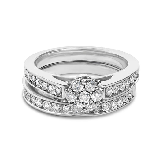 Close-up front angle of a white metal ring set featuring round white gemstones in prong settings arranged in a cluster on top and along the two bands.