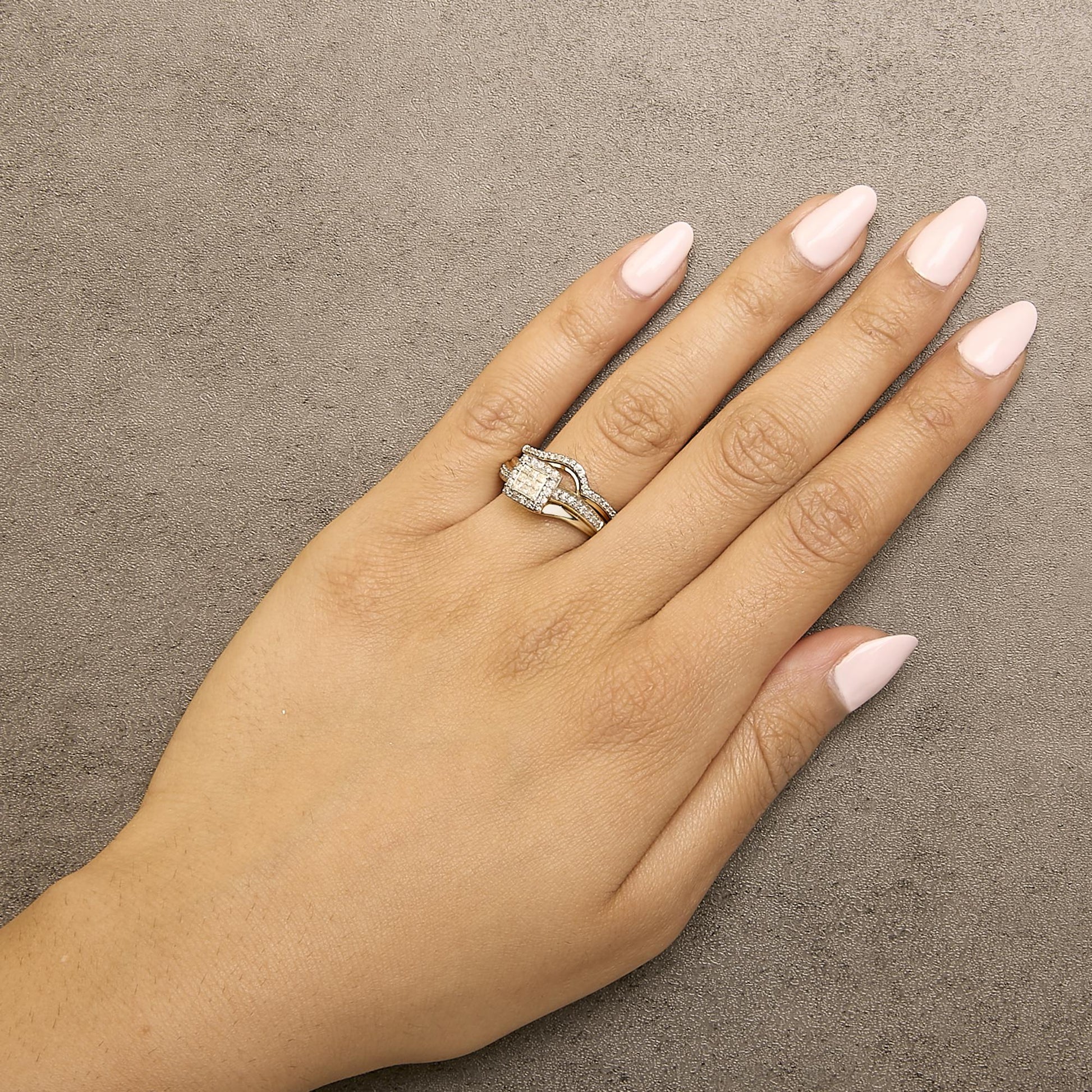 Yellow and white metal ring with princess shape and round shape white gemstones, shown worn on a model's hand from a top-down angle.