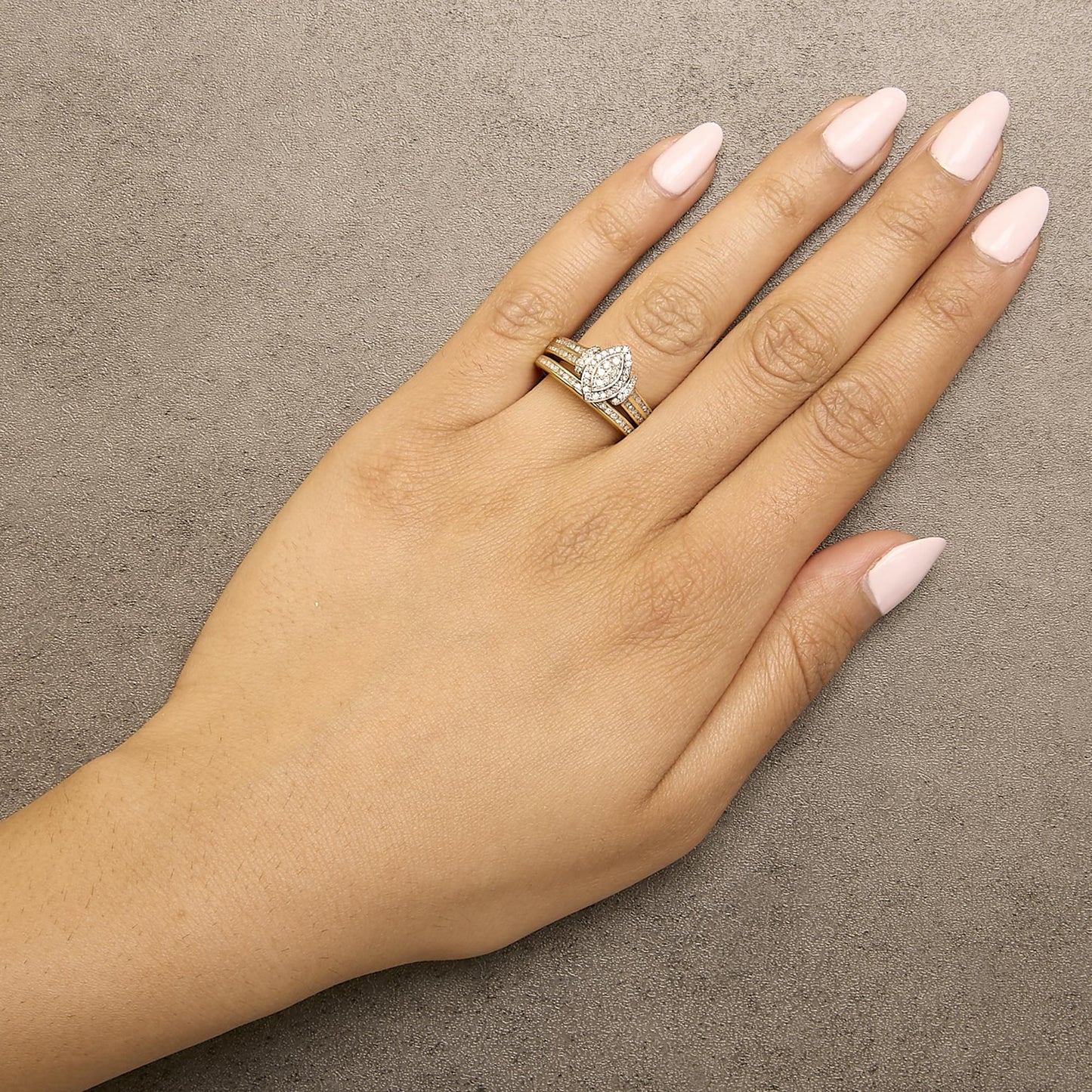 Close-up photo of a model's hand wearing a ring set with yellow and white metal bands and white round gemstones in an invisible setting, shot from above at an angle.