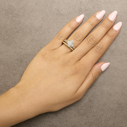 Close-up photo of a model's hand wearing a ring set with yellow and white metal bands and white round gemstones in an invisible setting, shot from above at an angle.