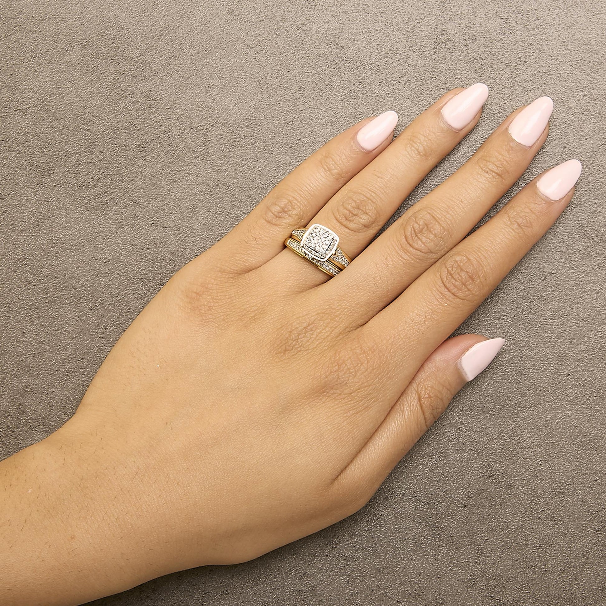 Ring with a square cluster of white round gemstones in prong setting and a split shank design in yellow and white metal, shown worn on a model’s hand from above at an angle.