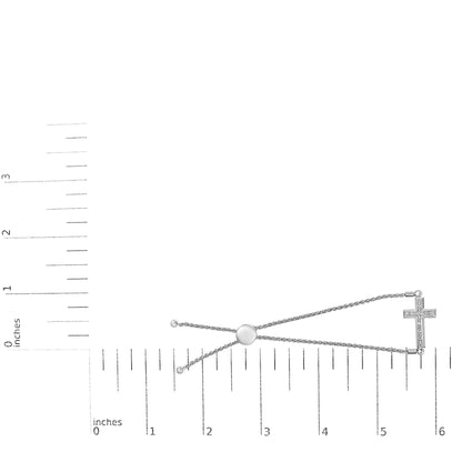 White metal bracelet with a cross pendant set with white round gemstones in pave setting, shown flat on a measuring scale, top-down angle.